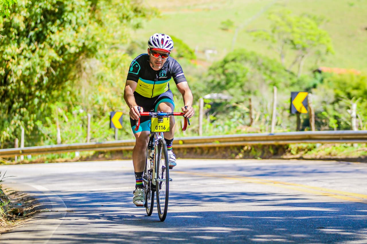 Artur Pereira pedalando em uma estrada, com capacete e uniforme de ciclismo, durante uma prova.